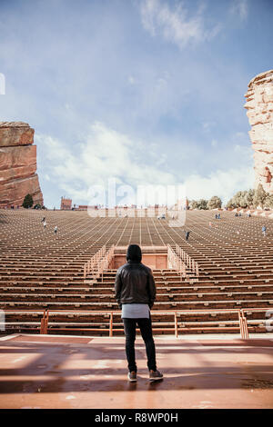 Ritratto simmetrica di persona in piedi su un palco di sognare mentre di fronte si erge Stadium posti a sedere presso l'anfiteatro all'aperto Concert Music Hall al di fuori Foto Stock