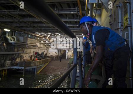 OKINAWA, in Giappone (14 marzo 2017) Boatswain compagno del marinaio Kelvin Wagner, da Houston, heaves in una linea di ormeggio all'interno del pozzo deck di trasporto anfibio dock nave USS Green Bay (LPD 20). Green Bay, parte dell'Bonhomme Richard Expeditionary Strike gruppo, con avviato 31 Marine Expeditionary Unit, è su una pattuglia di routine, operando in Indo-Asia-regione del Pacifico per migliorare la prontezza combattimento e la postura in avanti come una pronta risposta in vigore per qualsiasi tipo di emergenza. Foto Stock