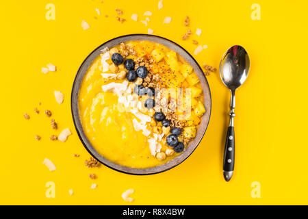 Piatto di laici frullato di mango vaso su sfondo giallo Foto Stock