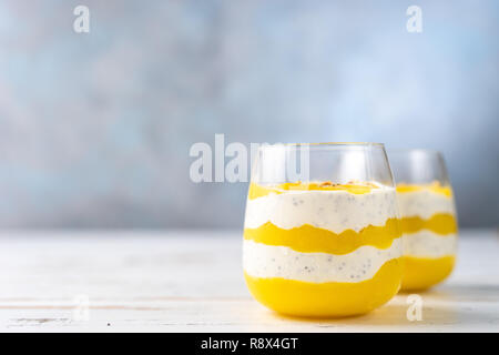 Frullato di mango con yogurt in due bicchieri su sfondo blu Foto Stock