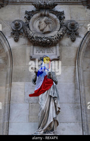 I manifestanti di giubbotti di giallo di dimostrazione (Gilets Jaunes) contro il governo e il presidente francese MESSI Maglia gialla e bandiera su Paris Opera Garnier Foto Stock