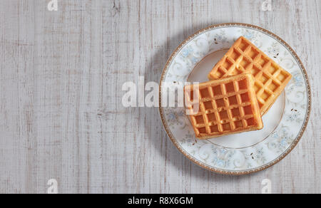 Vista superiore dolce fresco cialde Viennese sulla piastra isolata su un tavolo di legno. copia spazio. dolci per la prima colazione. Foto Stock