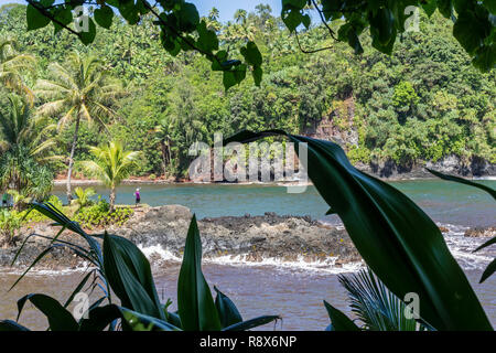 Papaikou, Hawaii - Una donna sulla riva del Onomea Bay sulla costa est dell'Isola Grande. Foto Stock