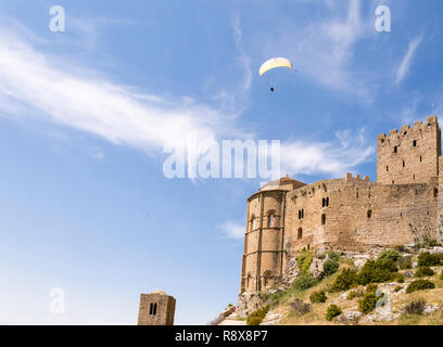 Parapendio nel cielo. Parapendio volare sopra il castello medievale di Loarre, Huesca, Spagna Foto Stock