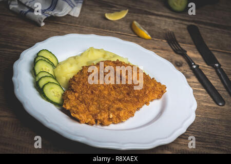 Chicken fried schnitzel con purè di patate e limone sul tavolo di legno Foto Stock