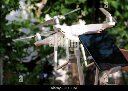 L uomo è in possesso di un drone in mano e di utilizzo delle nuove tecnologie. White quad copter fuco e fotografo man mano. Professional pilota drone detiene il pannello. Foto Stock