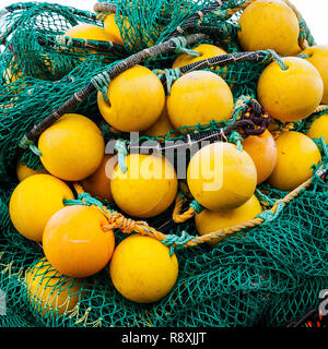 Pila di pesca gialla boe e il verde delle reti da pesca, su una banchina nel porto di Bergen, Norvegia Foto Stock