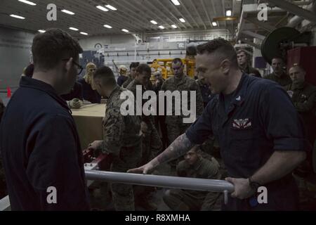 Mare delle Filippine (15 marzo 2017) Aviation Electronics Tecnico 1a classe Joshua Ellis, da Ellicott, Md., dà danno il controllo della formazione di marinai e marines in hangar bay a bordo Amphibious Assault nave USS Bonhomme Richard (LHD 6). Bonhomme Richard, ammiraglia del Bonhomme Richard Expeditionary Strike gruppo, con avviato 31 Marine Expeditionary Unit, è su una pattuglia di routine, operando in Indo-Asia-regione del Pacifico per migliorare la prontezza combattimento e la postura in avanti come una pronta risposta in vigore per qualsiasi tipo di emergenza. Foto Stock