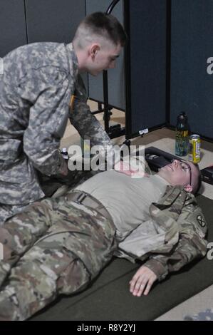 Stati Uniti Army Spc. Brett Johnson (sinistra) e SPC. Julian giovani, medici assegnati alla sede del Quartier Generale di truppe, 172nd reggimento di cavalleria, 86a brigata di fanteria combattere Team (montagna), Vermont Guardia nazionale, praticare la loro abilità di valutazione durante la bassa densità professionali militari specialty (MOS) formazione, Camp Johnson, Colchester, Vt., 4 marzo, 2017. I medici sono tenuti a rinnovare il loro medico di emergenza tecnico (EMT) certificazione ogni due anni per i loro MOS. Foto Stock