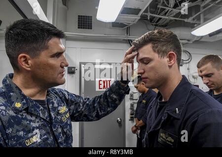 Sul mare del sud della Cina (1 marzo 2017) Lt. La Cmdr. Jeffrey Quinn (sinistra), Destroyer Squadron (DESRON) 1 cappellano, luoghi cenere sulla fronte del tenente j.g. Michael Murphy, da Indianapolis, Indiana, durante un mercoledì delle ceneri il servizio a bordo Arleigh Burke-class guidato-missile destroyer USS Wayne E. Meyer (DDG 108). Wayne E. Meyer è su un regolarmente programmati Pacifico occidentale di implementazione con la Carl Vinson Carrier Strike gruppo come parte dell'U.S. Flotta del pacifico-led iniziativa di estendere il comando e le funzioni di controllo di Stati Uniti 3a flotta nell'Indo-Asia-regione del Pacifico. Stati Uniti Navy portaerei strike gruppi Foto Stock