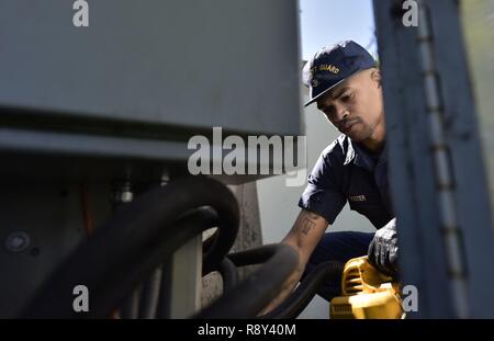 Petty Officer di terza classe Randy Doster, un macchinario tecnico assegnato alla Guardia Costiera di base in Alameda Alameda, California, aspirapolveri l'alloggiamento per un gruppo pompa idraulica sulla base, 27 febbraio 2017. L'unità controlla la base della porta principale, fornendo un sistema di protezione per centinaia di guardia costiera e i dipendenti civili che lavorano su base Alameda. Foto Stock