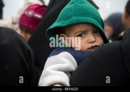 Un bambino attende in corrispondenza di una stazione di lavorazione per gli sfollati interni prima di essere trasportati in campi per rifugiati nei pressi di Mosul, Iraq, Marzo 03, 2017. Foto Stock