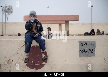 Un internamente sfollati bambino attende in corrispondenza di una stazione di lavorazione in preparazione per essere trasportati in campi per rifugiati nei pressi di Mosul, Iraq, Marzo 03, 2017. Foto Stock