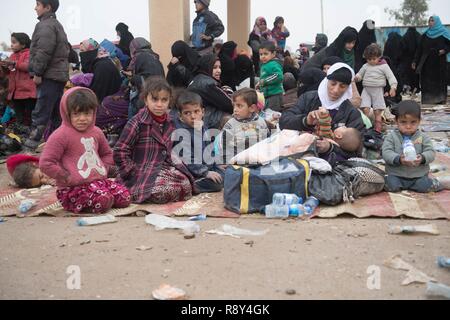 Le donne e i bambini in attesa in una stazione di lavorazione per gli sfollati interni prima di essere trasportati in campi per rifugiati nei pressi di Mosul, Iraq, Marzo 03, 2017. Foto Stock