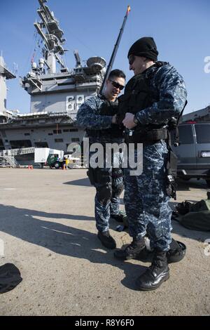 NORFOLK, Virginia (6 marzo 2017) Ensign Sean Jackson, sinistra, aiuta lo specialista culinaria 2a classe Justin Graham, prepararsi per una visita, scheda, ricerca e sequestro trapanare su un molo presso la Base Navale di Norfolk. Entrambi i marinai sono attualmente assegnati alle visite-missile destroyer USS Winston Churchill (DDG 81). Foto Stock