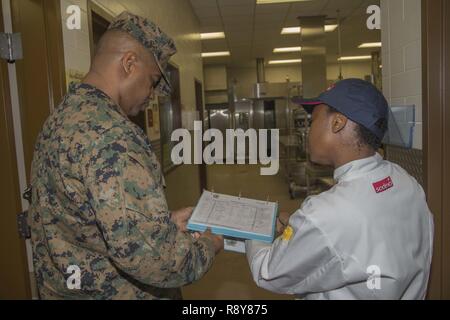 Stati Uniti Marine Corps Master Gunnery Sgt. Derreck Steele, sinistra, il personale non incaricato ufficiale responsabile, cibo servizio scolastico, Fort Lee, si consulta con Natalie Williams, responsabile di produzione, al fine di valutare il modo in cui il programma è eseguito in corrispondenza della zona 31 mess hall su Camp Pendleton, California, 7 marzo 2017. Il William Pendleton Thomas Hill concorso si è svolta a giudicare la migliore sala mensa in Marine Corps. Foto Stock