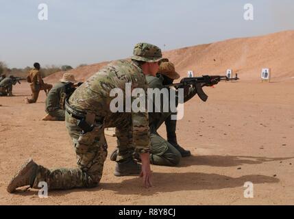 Un U.S. Le forze speciali soldato osserva come il Burkina Faso pratiche soldato sparare da un inginocchiarsi positiion, 6 marzo 2017 presso il Camp Zagre, Burkina Faso. Il giorno 7 della formazione i soldati si spara oltre 300 tornate dal vivo durante la pratica di diverse tecniche di ripresa. Foto Stock