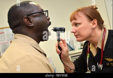 Il Jacksonville, Florida (3 marzo 2017) - Lt. La Cmdr. Janet West, un medico al ramo navale Health Clinic (NBHC) Jacksonville, esamina la gola del Chief Operations Specialist Navarro Evans, un marinaio attaccata alla Naval Air Station Jacksonville Area della flotta di controllo e di sorveglianza Facility. NBHC Jacksonville è uno del Naval Hospital Jacksonville le sei strutture sanitarie si trova in Florida e Georgia. Della sua popolazione di pazienti (163000 attivi e pensionati i marinai e soldati e marines, aviatori, guardie e le loro famiglie), quasi 85.000 sono arruolati con un primary care manager e Medical Home Foto Stock