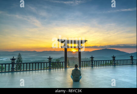 L'uomo meditando davanti il tempio come un modo per rilassarsi anima nel reame spirituale di pace di deposizione in cui Buddha porta in mattinata Foto Stock