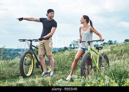 Guardare. Un uomo e una donna sono di ridere e camminare vicino a loro fatbikes Foto Stock