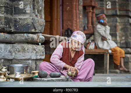 Naggar, India - 17 Luglio: vecchia donna Indiana che pulisce i piatti fuori del tempio. Piatti speciali che fanno offerte a Dio nel tempio. Luglio 17, 2013 Foto Stock