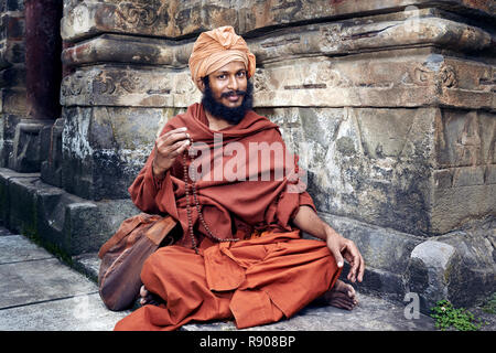 Naggar, India - 17 Luglio: Giovani yogi si siede vicino al tempio di Krishna. Si ripete il mantra segreto utilizzando un rosario. Il salmodiare 108 nome sacro di Dio. Luglio 1 Foto Stock