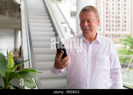 Happy businessman senior usando il telefono nella città Foto Stock