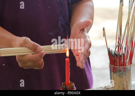 Buddisti di rendere merito,posizionando una candela accesa e incenso illuminato con candele telaio in corrispondenza del tempio. Messa a fuoco selettiva. Foto Stock