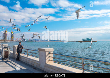 Baku/AZERBAIGIAN - Novembre 27, 2018. L'uomo alimentazione di gabbiani sul boulevard Foto Stock