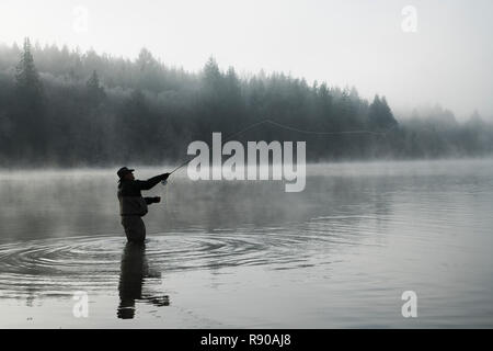 Silhouette del pescatore di Pesca a Mosca Report di Pesca del salmone e mare eseguire tagliagole trota in Puget Sound vicino a Olympia, Stati Uniti di Washington. Foto Stock