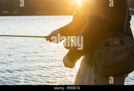 Una vista dettagliata in prospettiva di una mano di un pescatore a mosca per recuperare il suo linea da un cast che ha fatto in acqua salata. Foto Stock