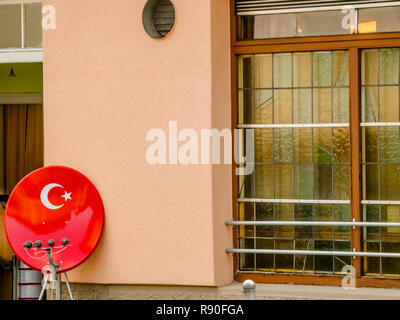 Ricevitore satellitare piatto nei colori del bagno turco bandiera nazionale di fronte ad un ristorante Foto Stock