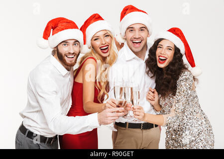 Il gruppo di quattro allegro ben vestiti amici in piedi isolato su sfondo bianco, per celebrare il Nuovo Anno, bevendo champagne Foto Stock