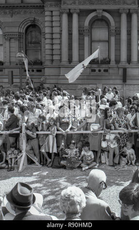 Sydney Australia, 13 marzo 1977: una folla di persone di tutte le età la linea delle barricate e wave e allegria presso l arrivo della Regina Elisabetta II e del Principe Filippo a Sydney piazza vicino al Municipio. La coppia reale ha partecipato ad un ricevimento civico con il sindaco, Leo porto e poi un servizio presso la vicina St Andrews Cattedrale. Sua Maestà la Regina e il principe sono stati in visita a Sydney insieme a numerose altre parti dell'Australia durante il mese di marzo come parte del loro Giubileo d'argento world tour. Credito foto Stephen Dwyer (Età 17) Foto Stock