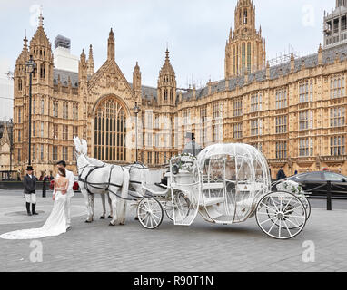 Il cinese coppia sposata vestito di bianco rappresentano per la fiaba foto di nozze, con bianchi carrozza trainata da due cavalli bianchi, al di fuori del parlamento di Londra. Foto Stock