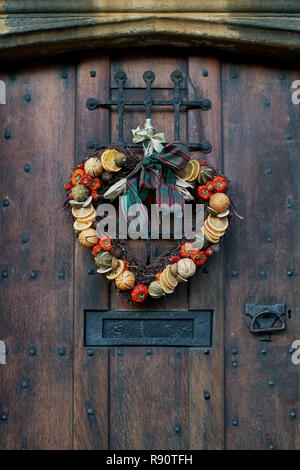 Cuore di Natale corona su una vecchia casa in legno porta in Chipping Campden, Cotswolds, Gloucestershire, Inghilterra Foto Stock