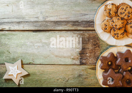 Piatto di laici tavola in legno rustico con scaglie di cioccolato e a forma di stella i cookie in piatti di ceramica. Con copia spazio. Foto Stock