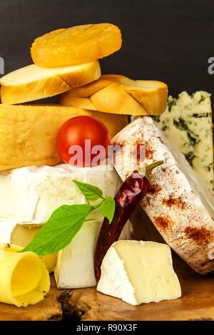 Vari tipi di formaggio servita su un tavolo di legno. Tavola di legno con diversi tipi di squisiti formaggi sulla tavola. Vendita di formaggi. Cibo sano. La proteina Foto Stock