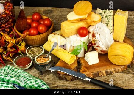 Vari tipi di formaggio servita su un tavolo di legno. Tavola di legno con diversi tipi di squisiti formaggi sulla tavola. Vendita di formaggi. Cibo sano. La proteina Foto Stock