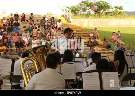 Stati Uniti I soldati dell esercito con la 721st Guam Esercito Nazionale banda di guardia e i musicisti con il Pacific Saipan venti Concert Band prepararsi ad eseguire un numero musicale per il pubblico all'American Memorial Park anfiteatro in Saipan, Repubblica della Mariana Islands settentrionale, Dicembre 9, 2018. Il concerto è stato organizzato come un modo per dire "grazie" per la comunità per il loro sostegno ai militari durante il Super Typhoon Yutu soccorsi. Foto Stock