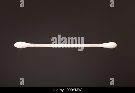 Close up di un singolo in plastica orecchio di cotone bud contro uno sfondo grigio. Foto Stock