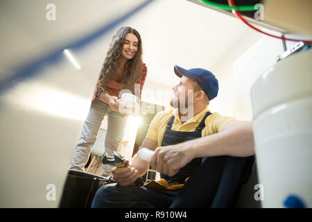 Piuttosto proprietario di casa dando il caffè per idraulico Foto Stock