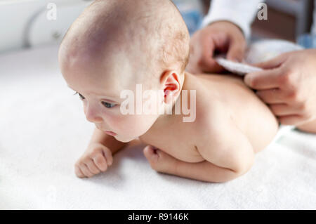 Giovani papà cambia il pannolino per il suo neonato bambino piccolo. Messa a fuoco selettiva Foto Stock