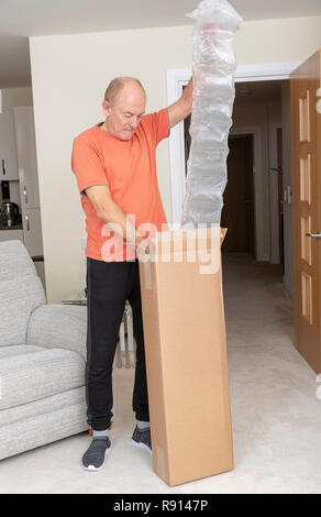 L'uomo disimballaggio un marrone scatola in cartone contenente una quantità eccessiva di aria di protezione sacchetti Foto Stock