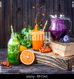 Succo di frutta fresco e frullati con frutti di bosco e frutta e spinaci verdi su sfondo di legno Foto Stock