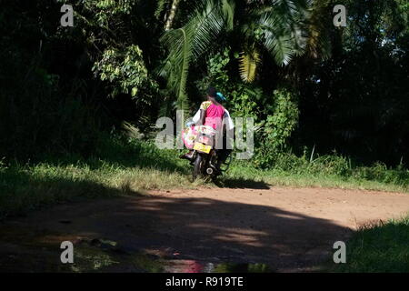 Un uomo e una donna su una moto su una strada sterrata in Uganda Foto Stock