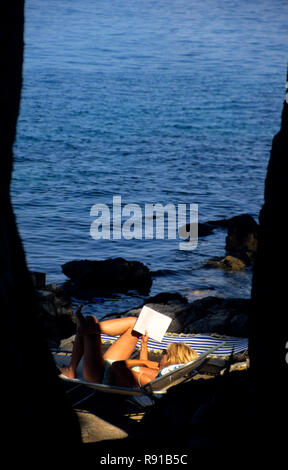 La donna posa su una sedia a sdraio in costume da bagno la lettura di un libro, Bozava, Dugi otok croazia Foto Stock