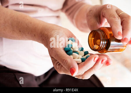 Primo piano di un senior donna caucasica con un mucchio di diverse pillole in mano Foto Stock