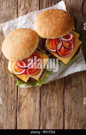 Hamburger Vegetariano con lattuga fresca, cipolle, pomodori e il formaggio cheddar vicino sul tavolo. Verticale in alto vista da sopra Foto Stock
