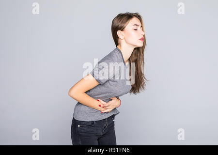 Studio Ritratto di giovane donna avente una stomachache, le mestruazioni dolore o crampi, isolato su sfondo grigio. Foto Stock